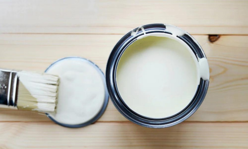 Overhead view of an open white paint can with paint brush set next to it